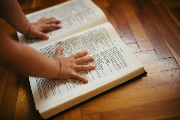 Kinderhände auf aufgeschlagenem Wörterbuch